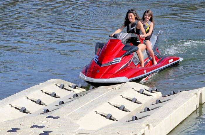two riders on a jet ski pulling up on a portable docking system